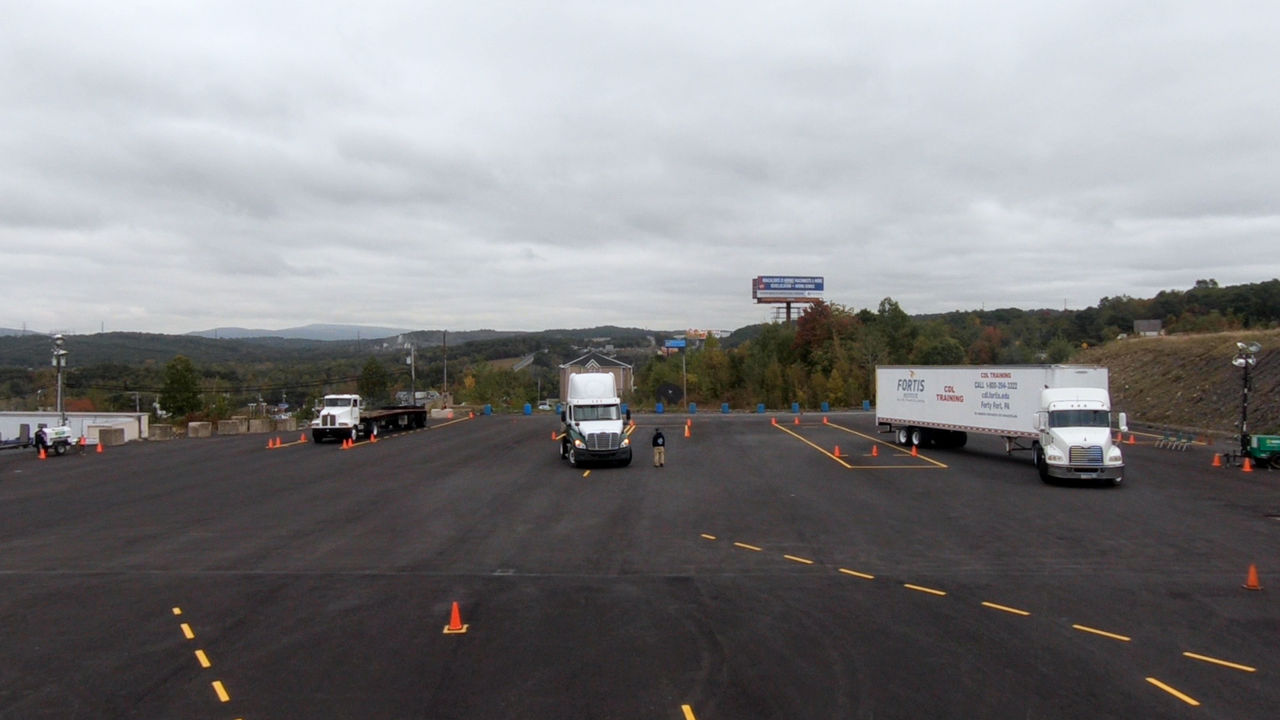 Trucks parked in large open asphalt lot on cloudy day