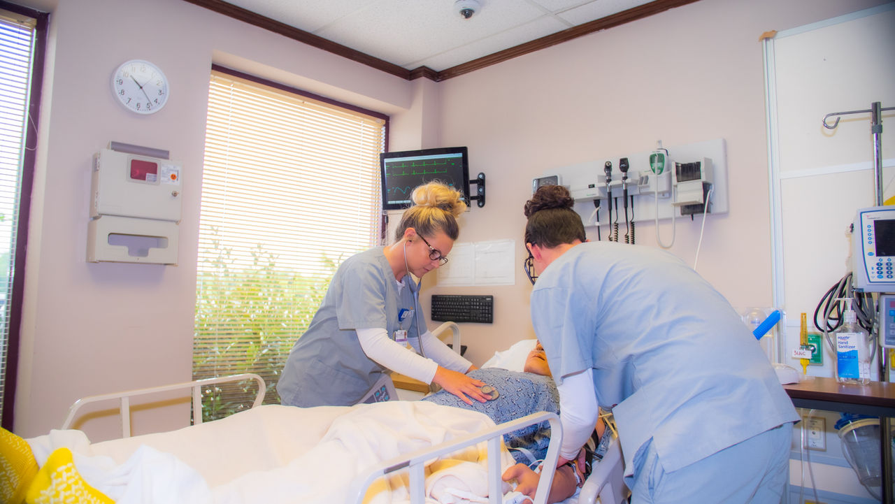 Nurses caring for patient in hospital room